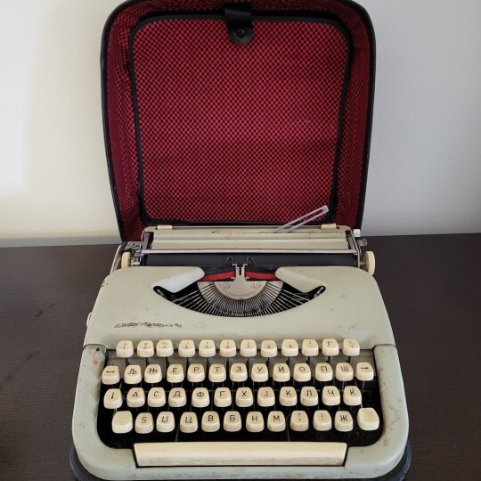 Image of Cyrillic alphabet, vintage portable manual typewriter with a case